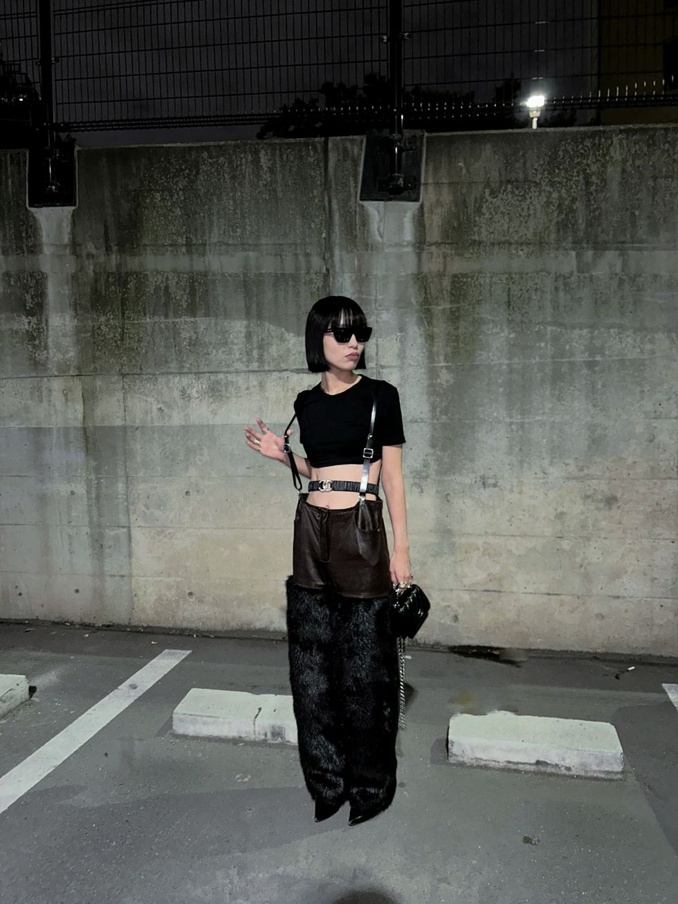 a person wearing a black dress and sunglasses standing in a parking lot
