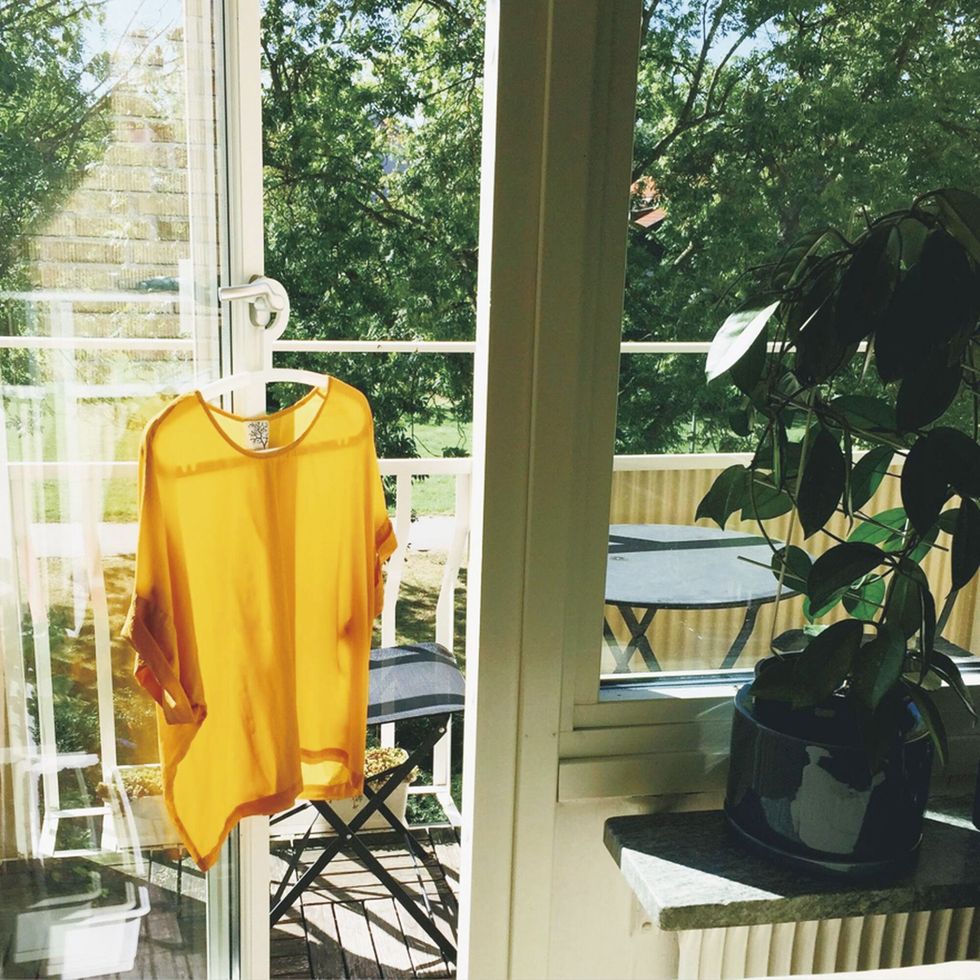 a yellow and orange striped chair next to a window with a table and chairs and a plant