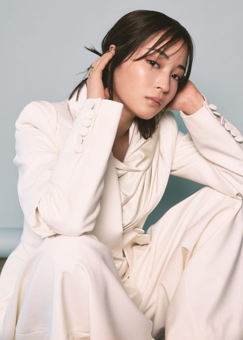 a person wearing a stylish white outfit seated in a thoughtful pose
