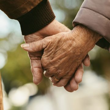 elderly couple holding hands and walking