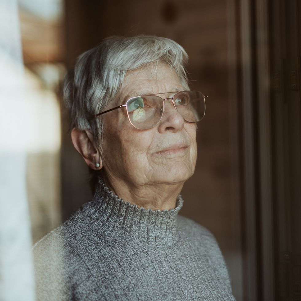 elderly woman looking out of a window
