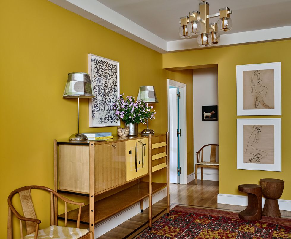 a chartreuse yellow room with a wood side table and chairs and artwork