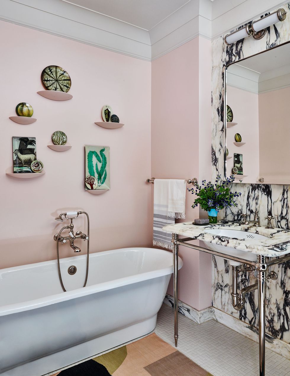 pink bathroom with standalone tub and metal washbasin and black and white marblized wall and plates on the wall