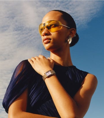 woman wearing a dark outfit and a stylish watch against a blue sky