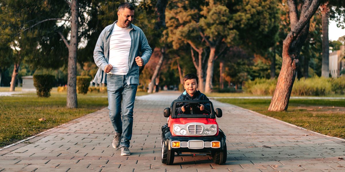 dad running alongside kid riding electric car