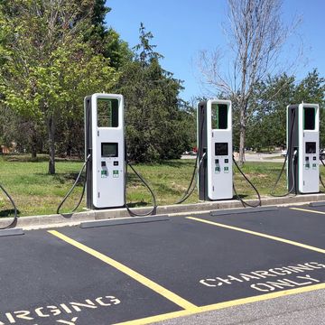electric charging station with many electric chargers and a parking lot on a sunny day