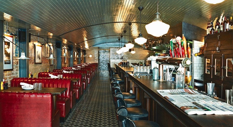 interior of a bar and restaurant with red booths and a long wooden counter