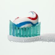Electric toothbrush with toothpaste against white background, close up