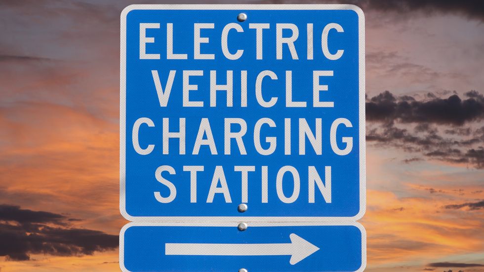 electric vehicle charging station sign with sunset sky
