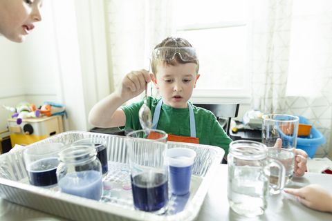 elementary age boy focused doing chemistry science experiment at home