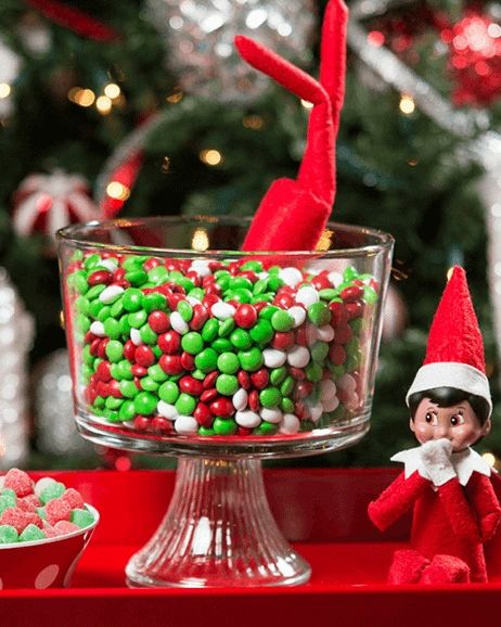 elf on the shelf dove head first into deep dish of holiday m and ms, his legs waving in the air