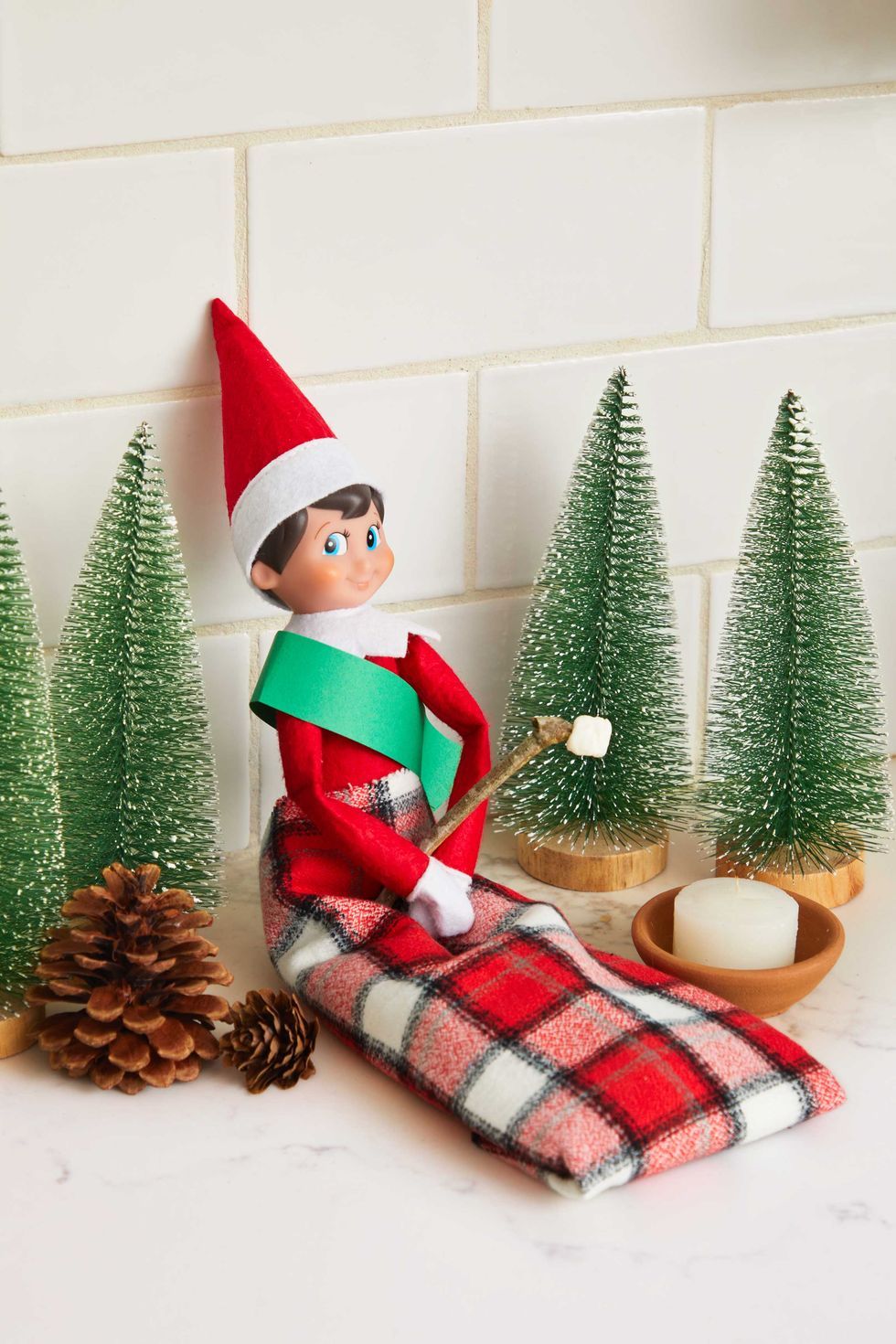 elf on the shelf doll in a plaid sleeping bag