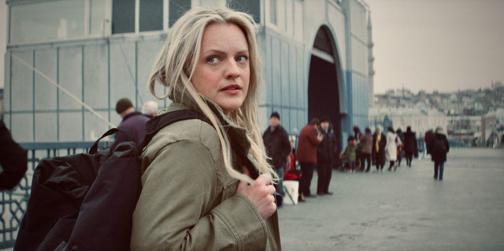 a person stands on a promenade with a crowd of people in the background