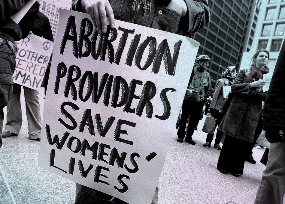a rally participant holds a sign that reads "abortion providers save womens' lives" during an international women's day march in chicago