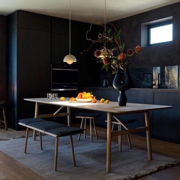a dark kitchen with black cabinets and a long wooden dining room table