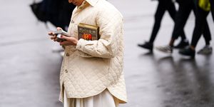 paris, france   february 27 a guest wears earrings, a cream color quilted jacket, an alice in wonderland book clutch, outside ann demeulemeester, during paris fashion week   womenswear fallwinter 20202021, on february 27, 2020 in paris, france photo by edward berthelotgetty images