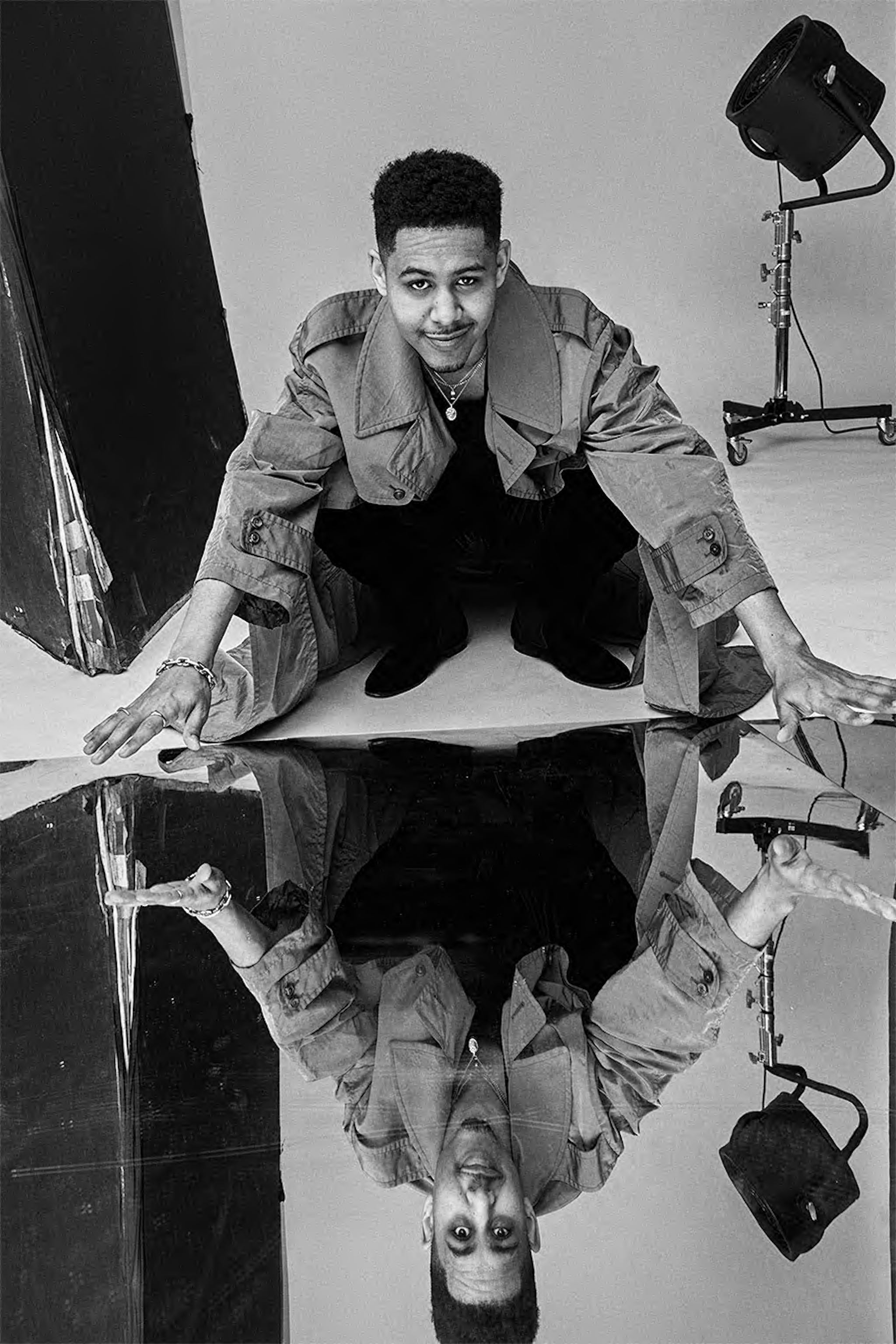 a person crouching near a reflective surface with studio lighting