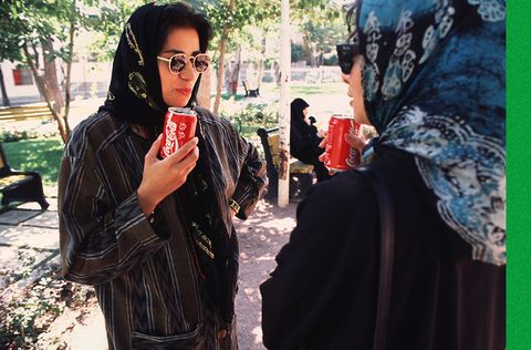 zwei frauen mit bunten schleiern und sonnenbrillen trinken coca cola aus dosen in einem park im norden teherans, iran, mai 1995 foto von kaveh kazemigetty images