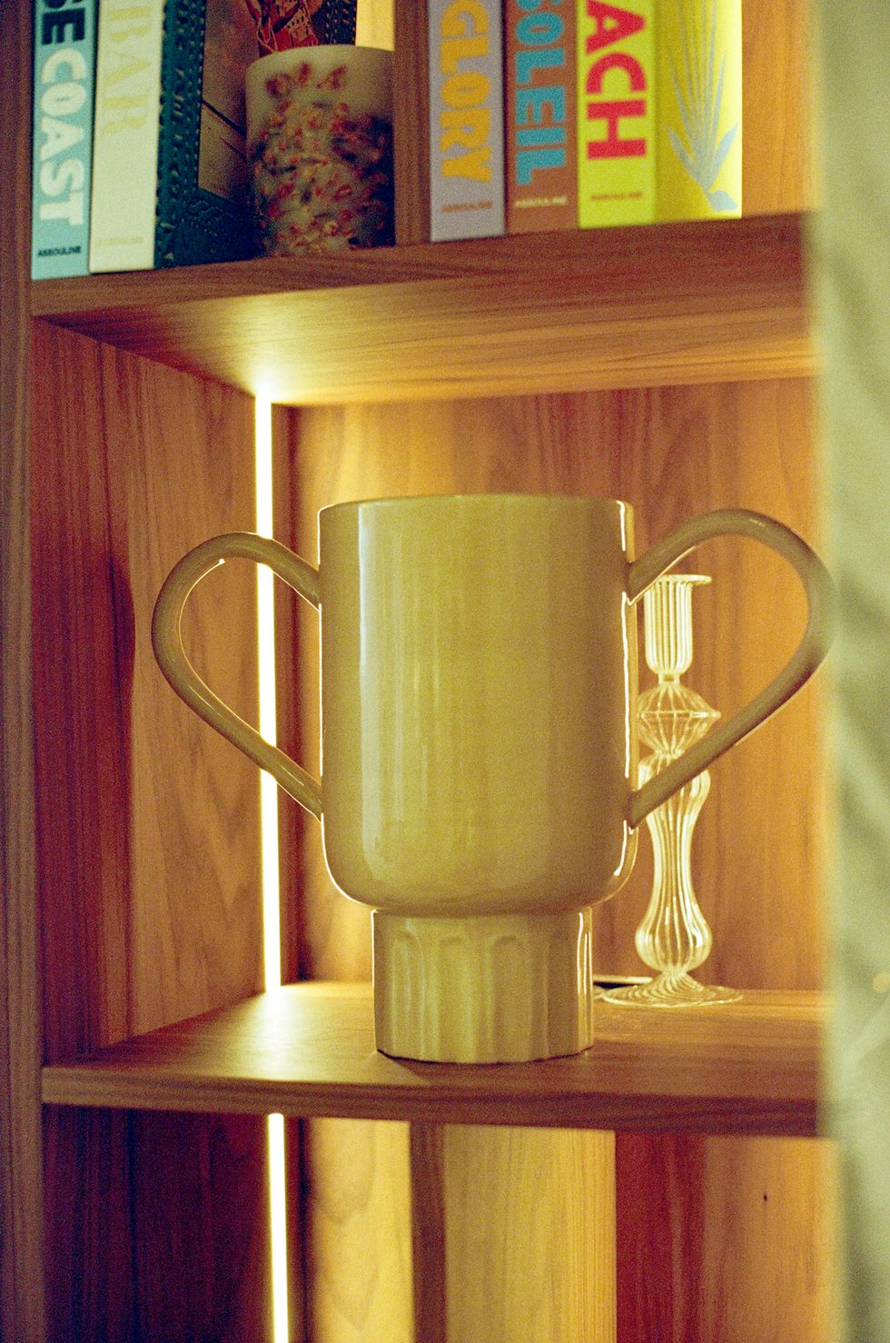 a gold and silver mug on a wooden shelf