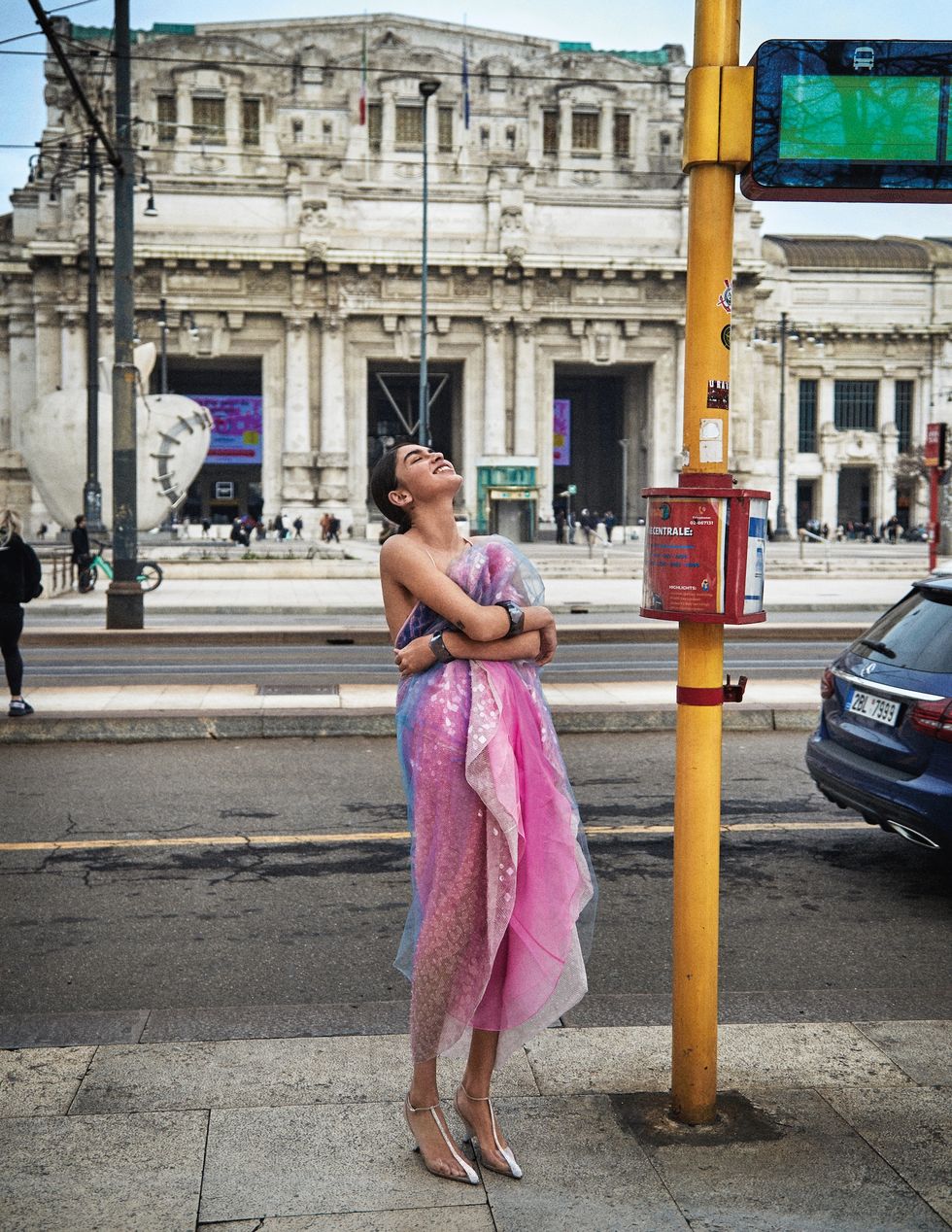 a woman in a pink dress standing on a street corner