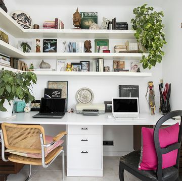 oficina en casa con dos sillas, mesa doble con dos ordenadores, estantería y plantas