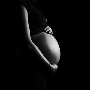 7 month pregnant belly isolated on a black background high contrast black white