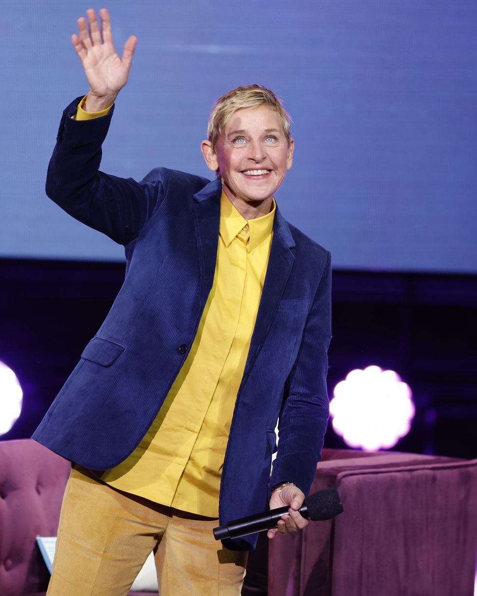 ellen degeneres waving to an audience with her right hand while taking the stage for a panel