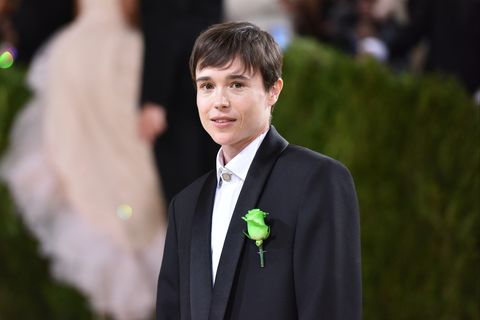 elliot page on red carpet wearing a black suit with green rose pinned to jacket