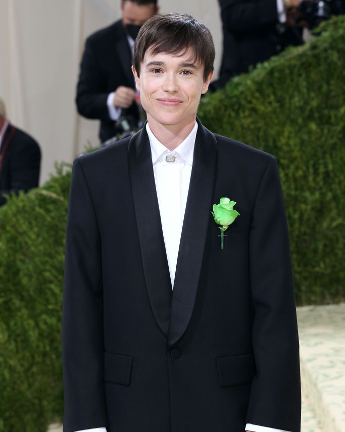 elliot page wears an oversized black suit and a green carnation pin on the red carpet
