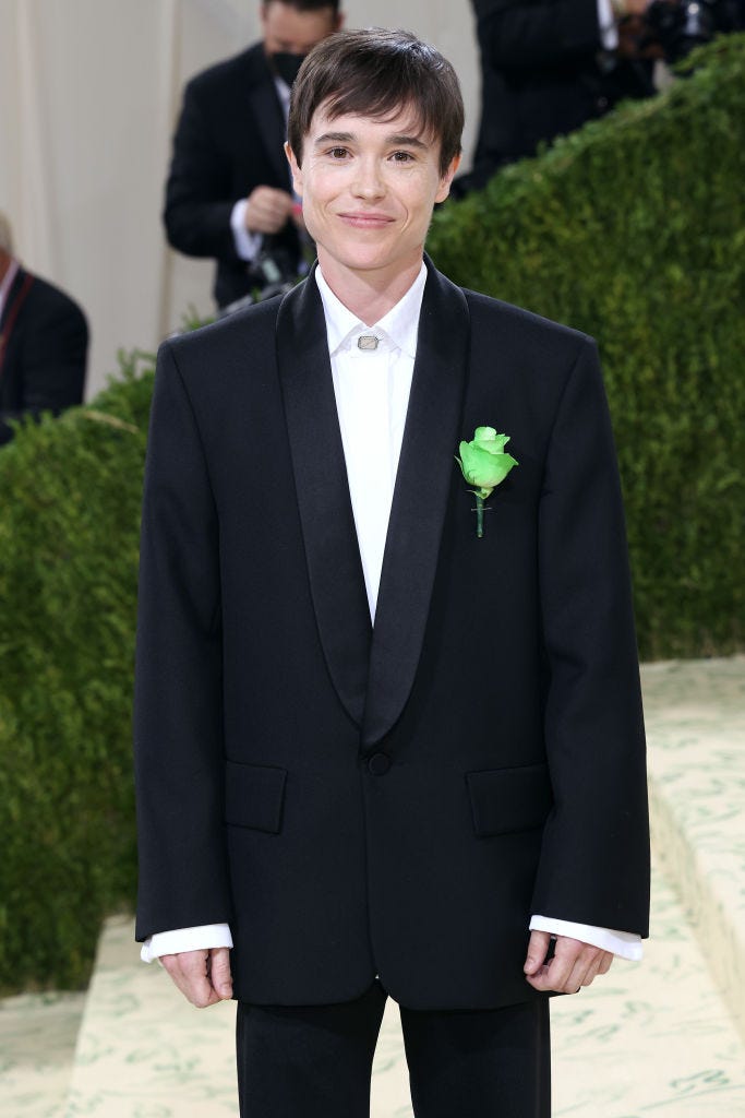 elliot page wears an oversized black suit and a green carnation pin on the red carpet