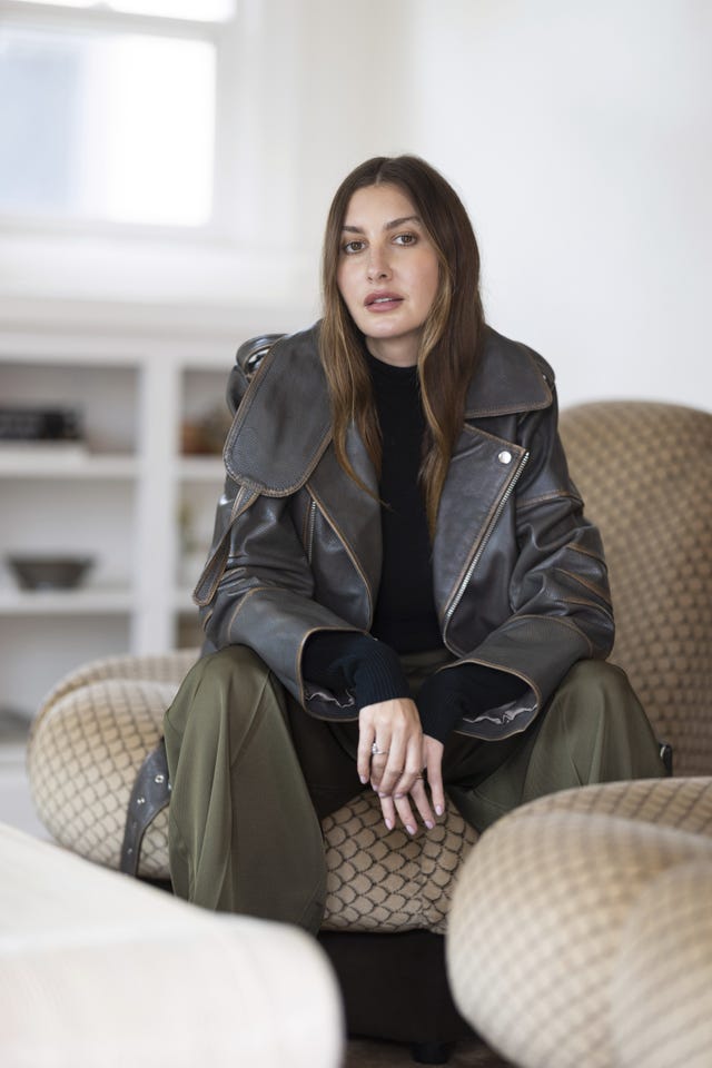 allison bornstein sitting in a cozy chair wearing a stylish outfit