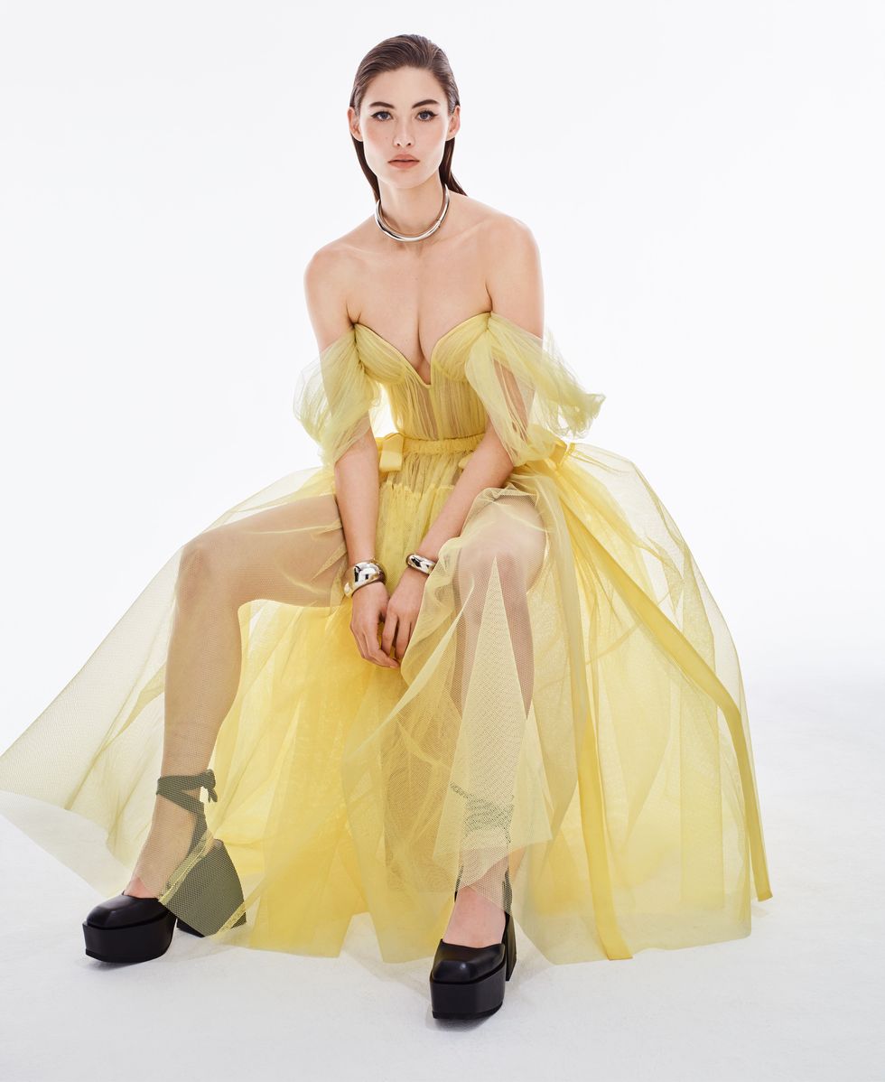 grace elizabeth sits in a yellow tulle dress wearing patent leather platform heels