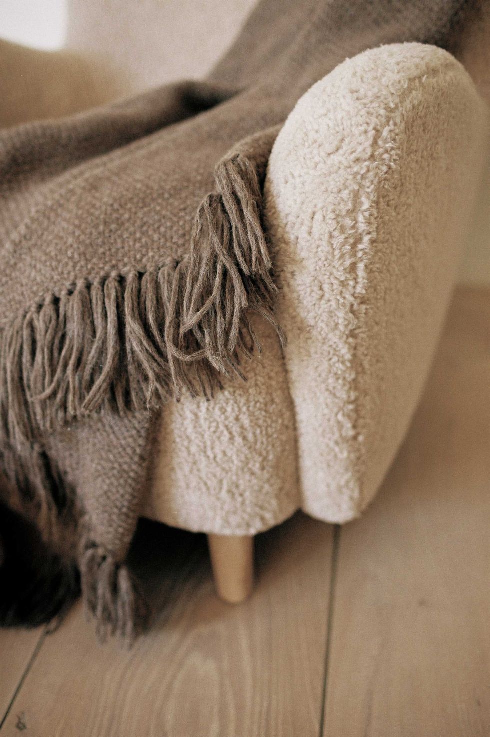 a throw blanket is tossed over a cozy boucle chair