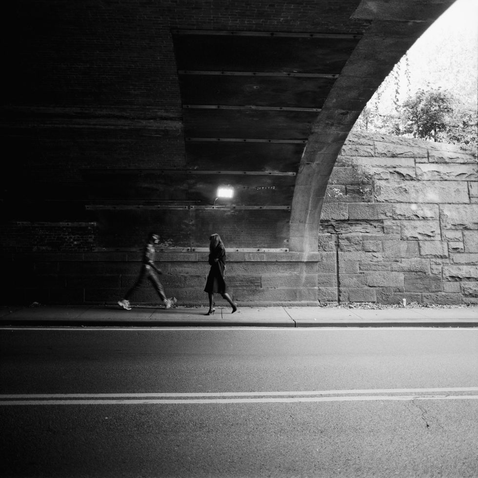 a couple of people walking under a bridge at night