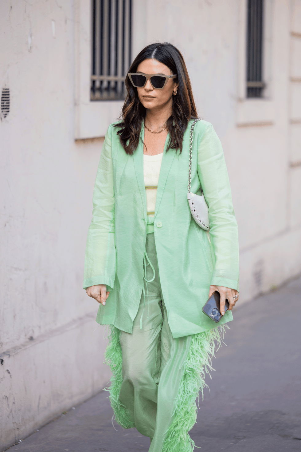 a brunette woman wearing a green suit with feathers