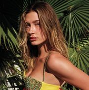 hailey bieber stands in front of palm trees, wearing a bejeweled bustier top
