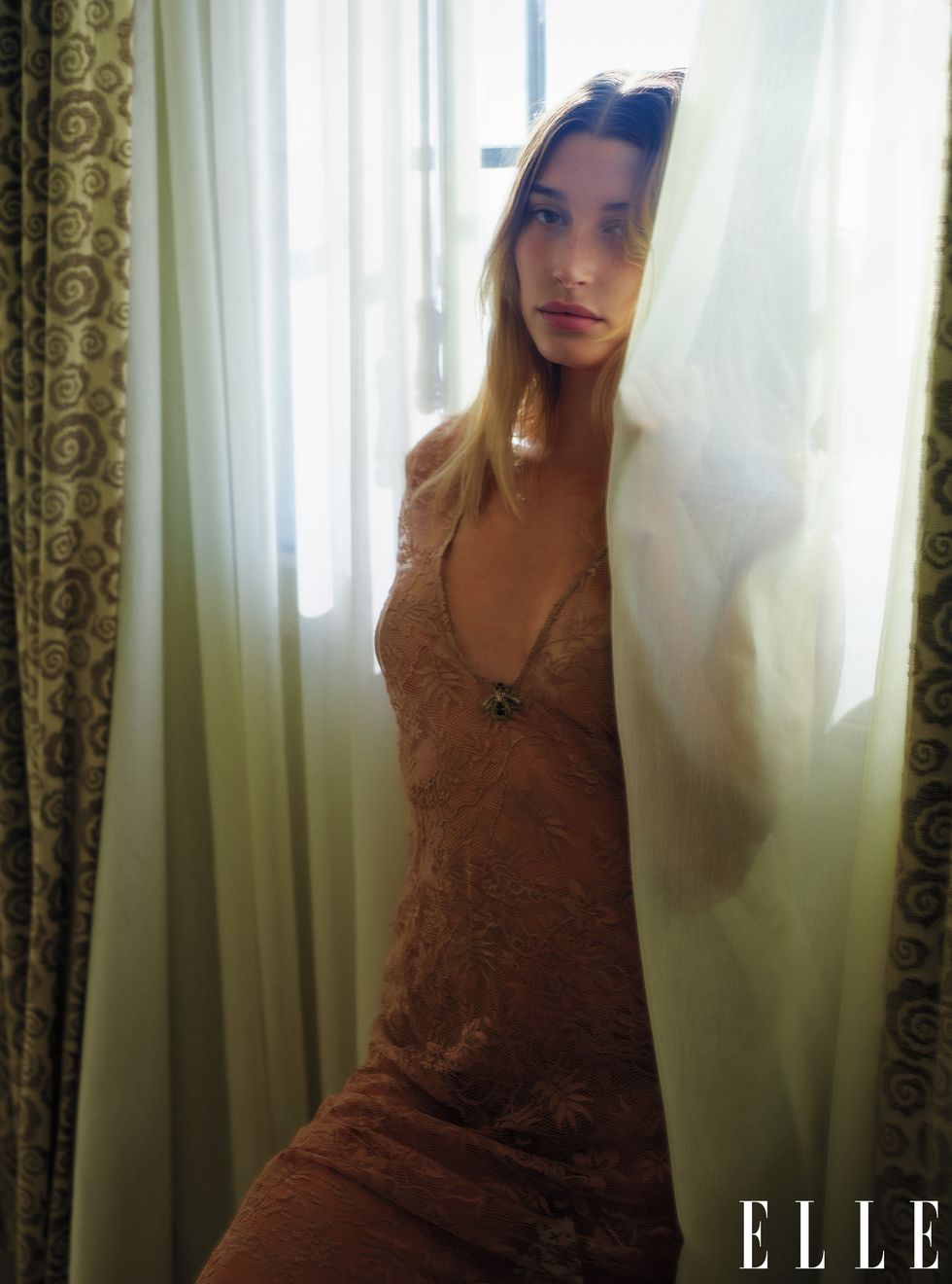 hailey baldwin stands among the draperies in a dress