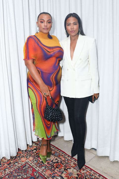a woman in a multicolored dress and a woman in a white blazer and black leggings