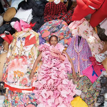 a black woman in a pink gown lying in a pile of colorful clothing