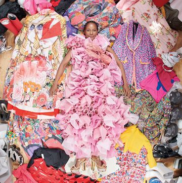 a black woman in a pink gown lying in a pile of colorful clothing