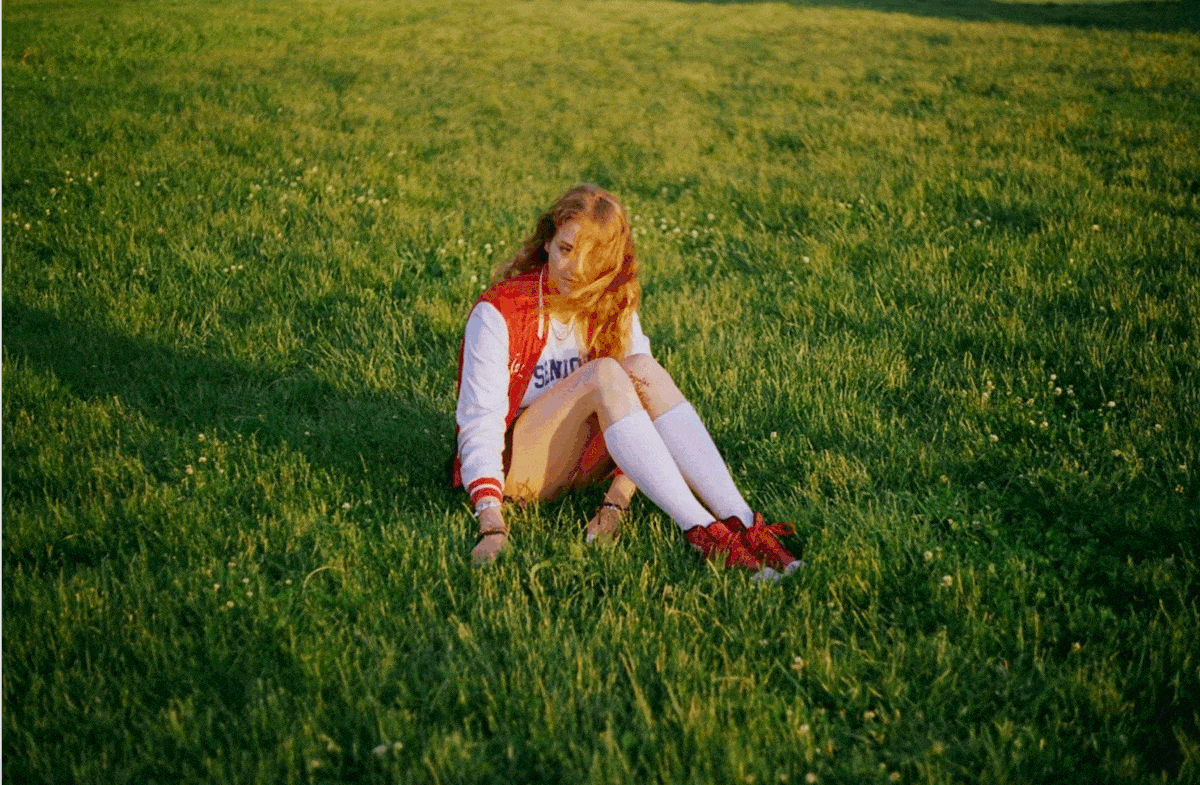 a young girl sits in the grass