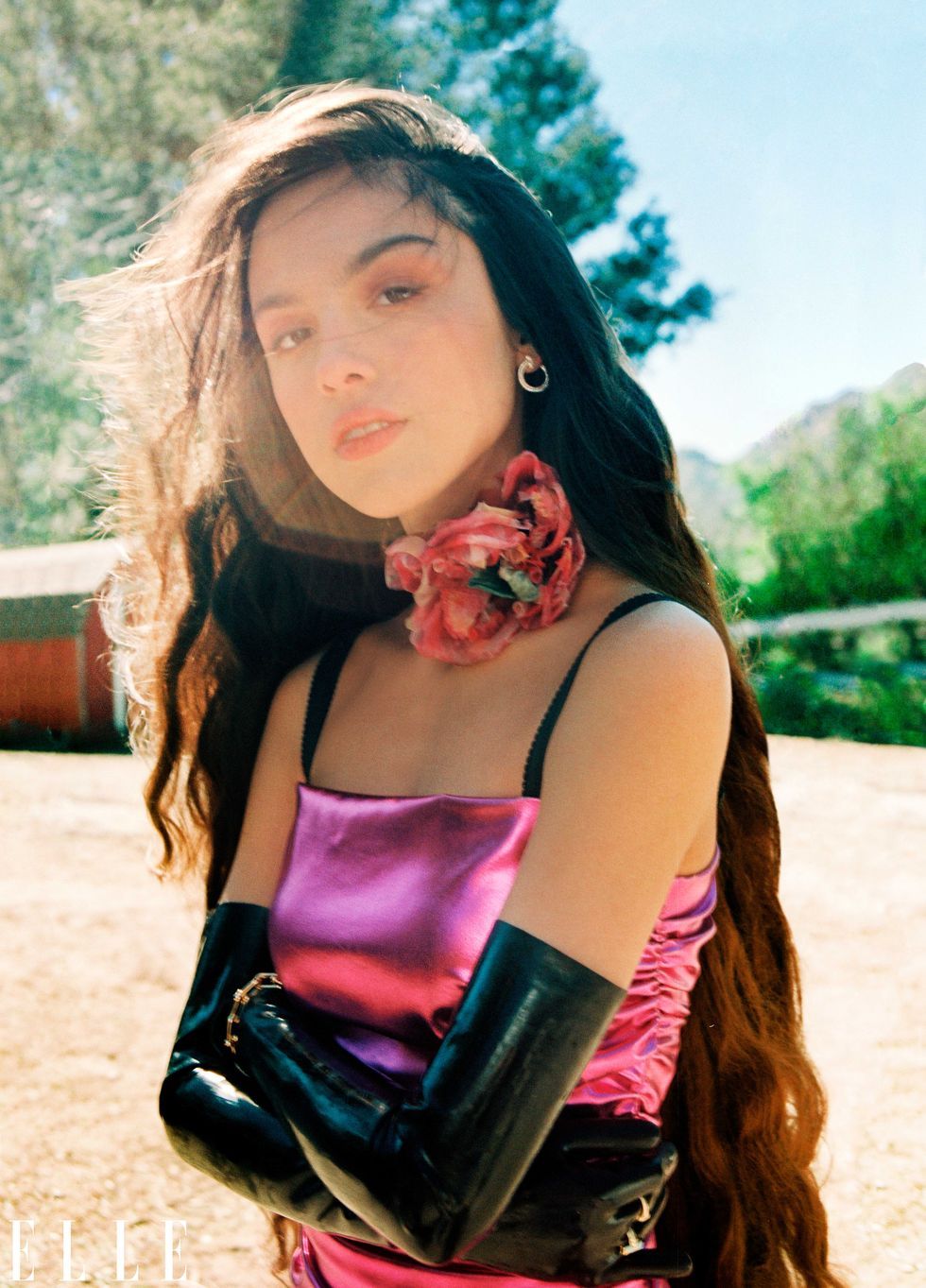 olivia rodrigo sH๏τ outside with arms crossed, wearing H๏τ pink satin dress, long black gloves and a floral choker