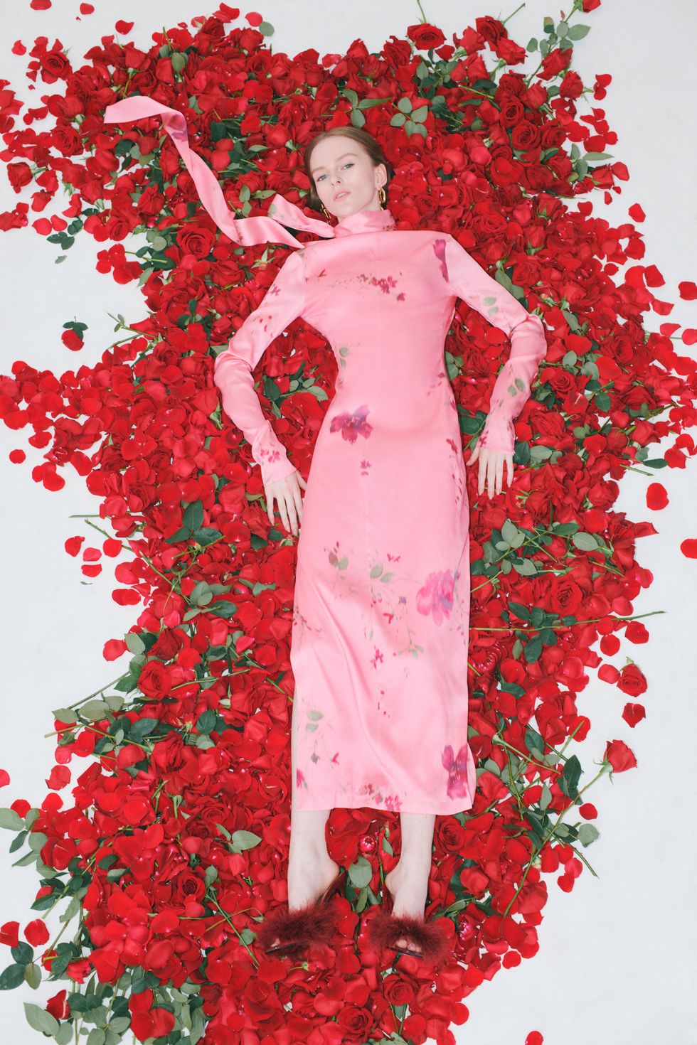 a woman in a pink dress lying on flower petals