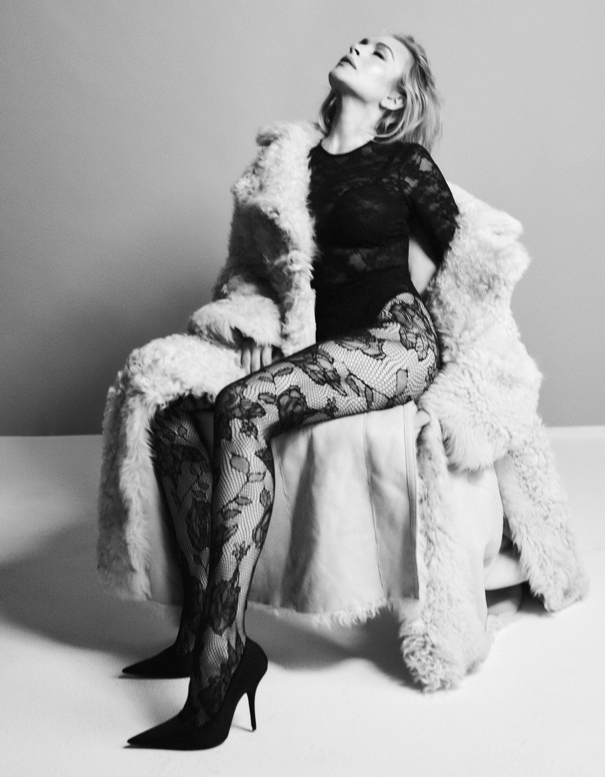 lindsay lohan sitting elegantly on a plush chair wearing lace and heels