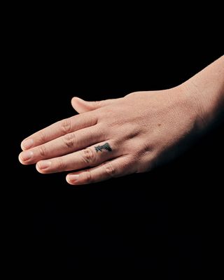 a hand with a chess piece ring finger tattoo