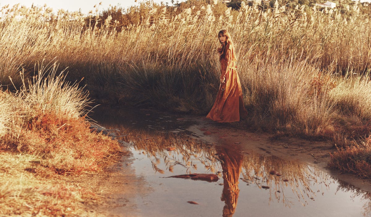 a person in a dress standing in a swamp
