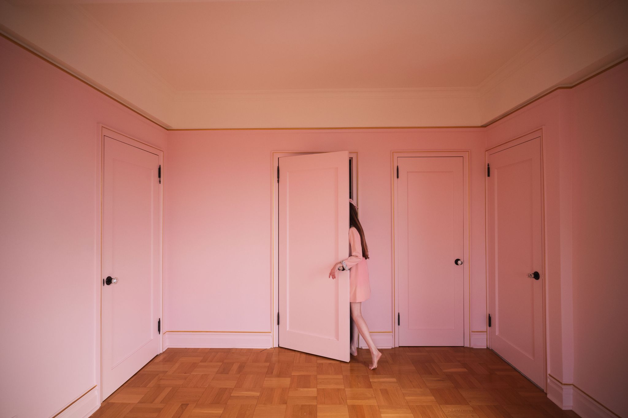a woman in a dress standing in a room with pink doors