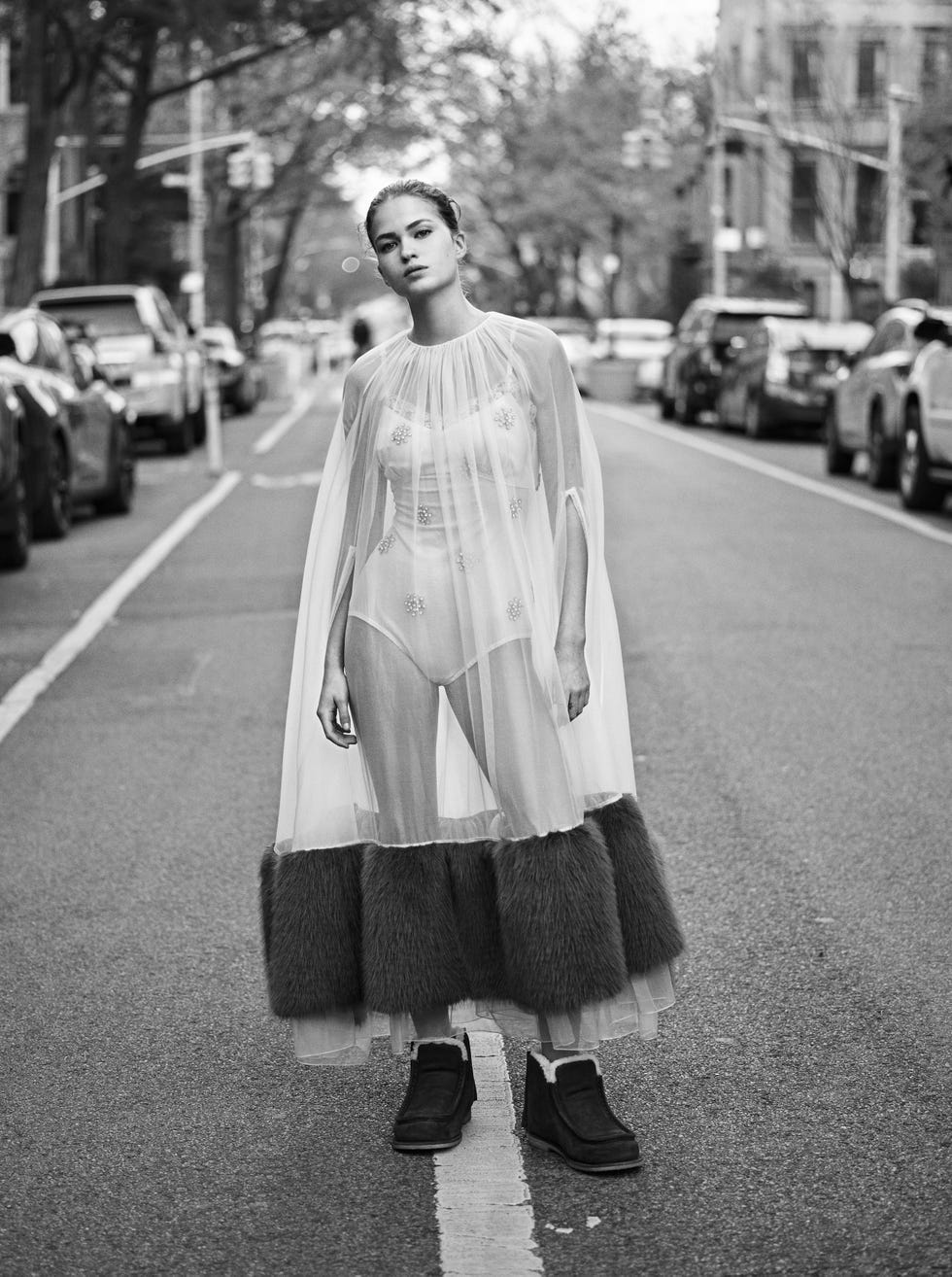 a woman in a transparent cape standing in the middle of a street