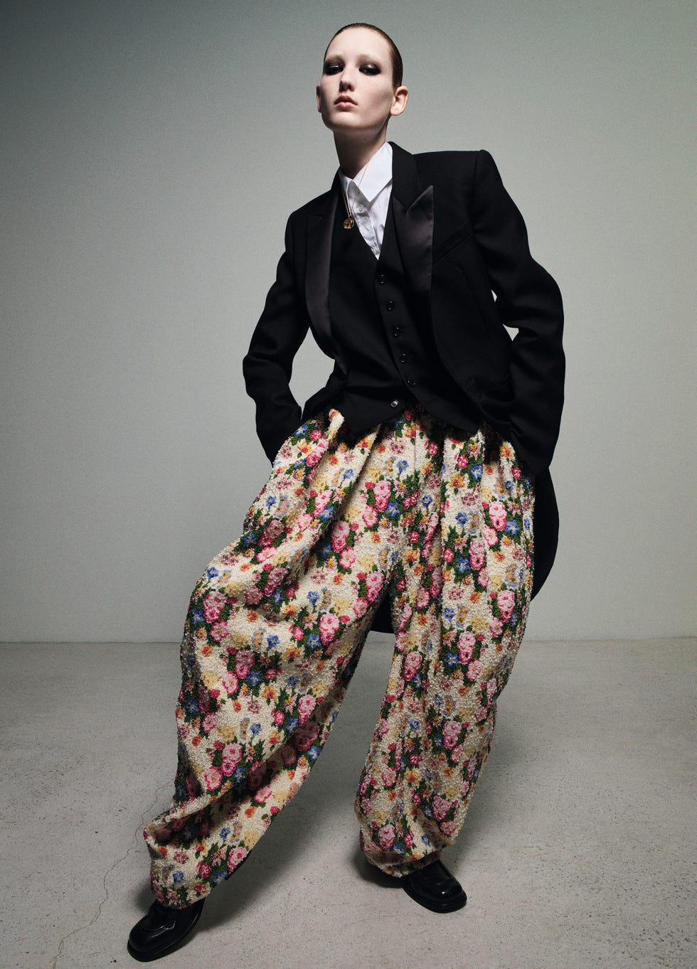 a woman wearing a suit jacket and oversized floral pants