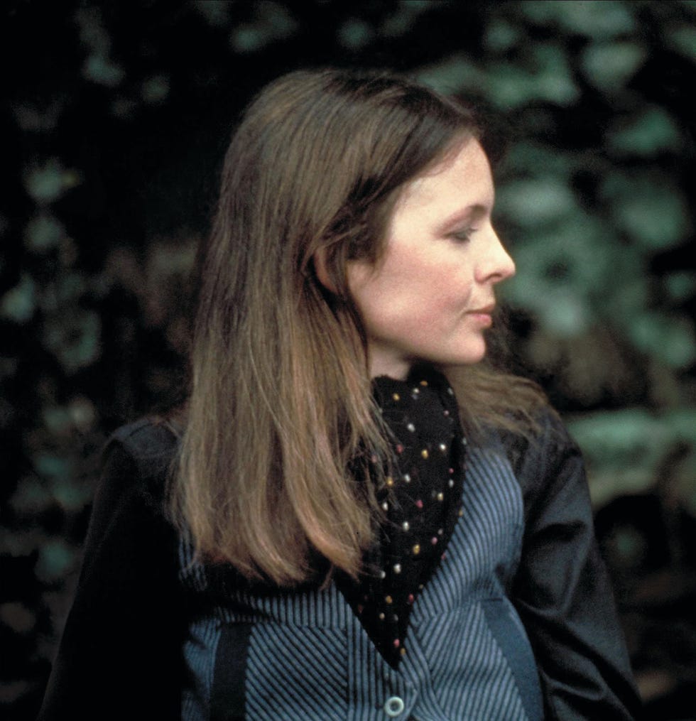 a brunette woman wearing a vest and turning to the side